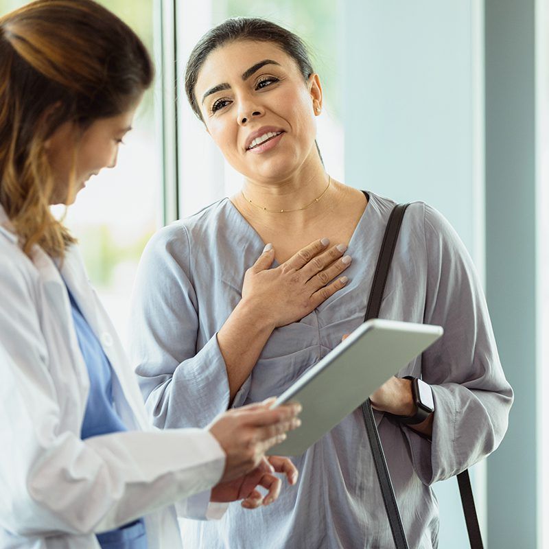 The mid adult female patient is relieved when the doctor gives her good news about the test results.  The mid adult female doctor uses a digital tablet.